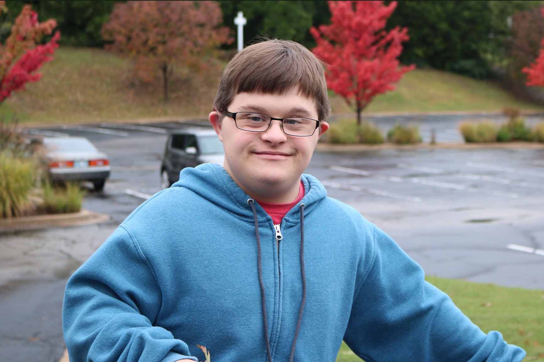 Male student Ethan, outside, wearing a light blue zip up hoodie.