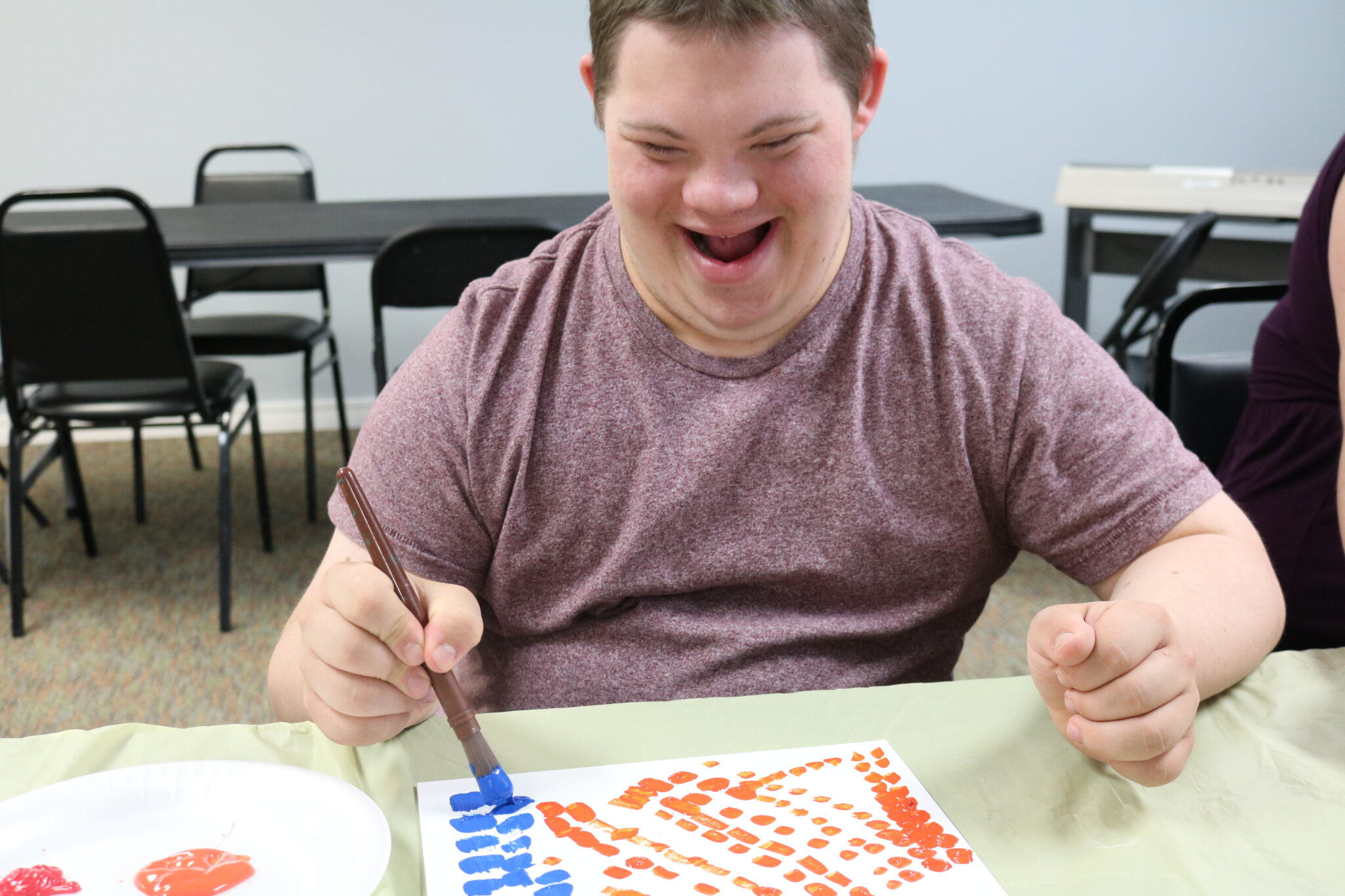 A student painting, with a big smile on his face.