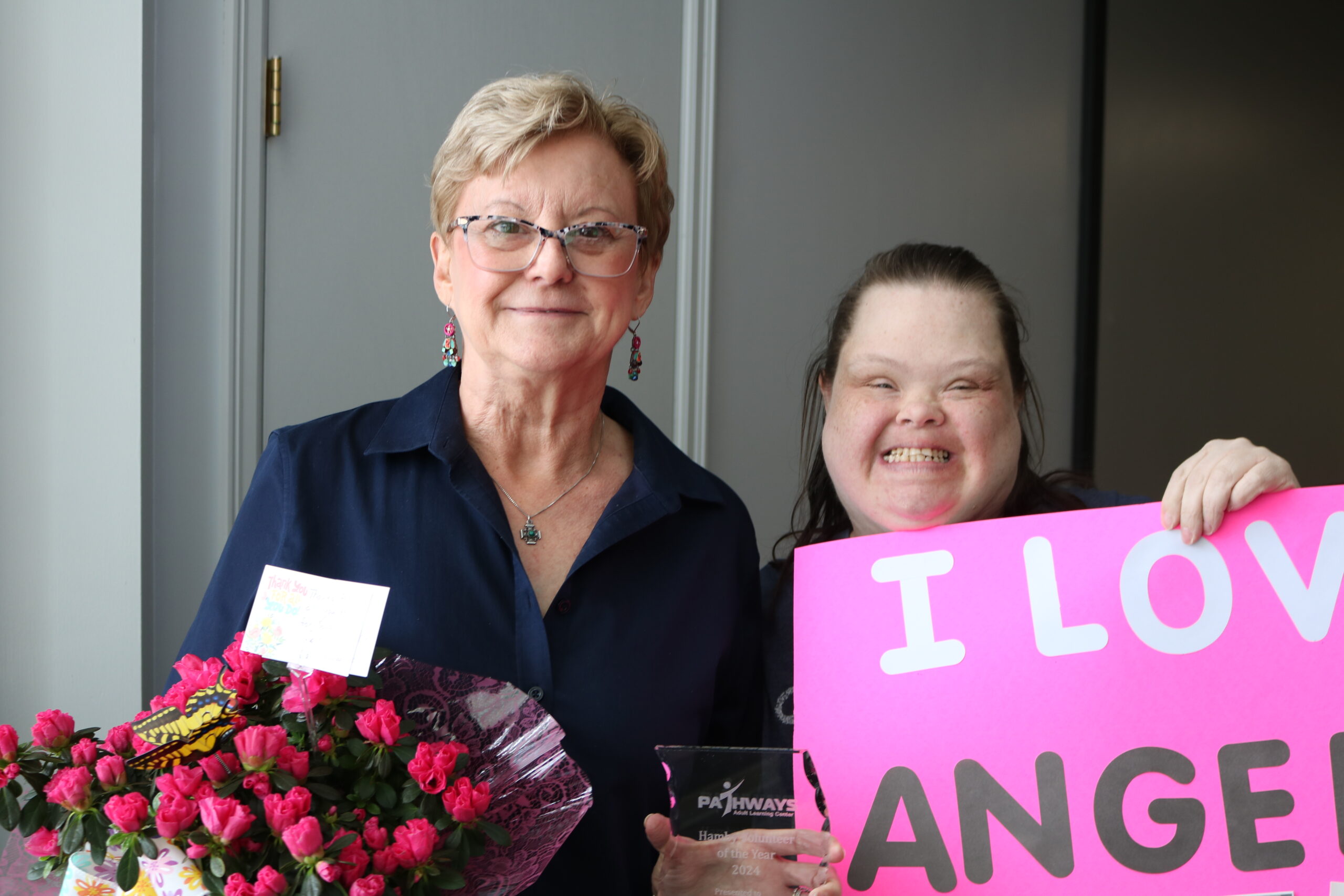 Our student Angela, pictured with our Volunteer of the Year, Sara - who is holding a bouquet of flowers and an award.