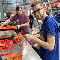 Pathways student Josh putting carrots in a mesh bag at the food bank.