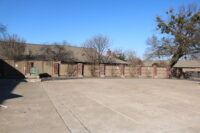 A photo of a fence and parking lot