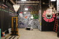 A photo of a wall with a lot of graffiti type art and many chandeliers 