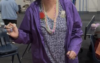 A Pathways student holding a sharpie and standing over a wood board .