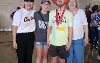 Pathways student Josh Miller at Special Olympics wearing the silver medal he earned in the 100 meter race surrounded by his family.