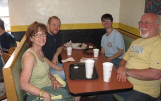 Clint and Rebecca Whisenhunt smiling and eating lunch with two Pathways students.