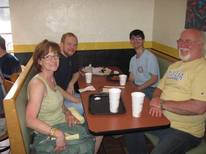 Clint and Rebecca Whisenhunt smiling and eating lunch with two Pathways students.