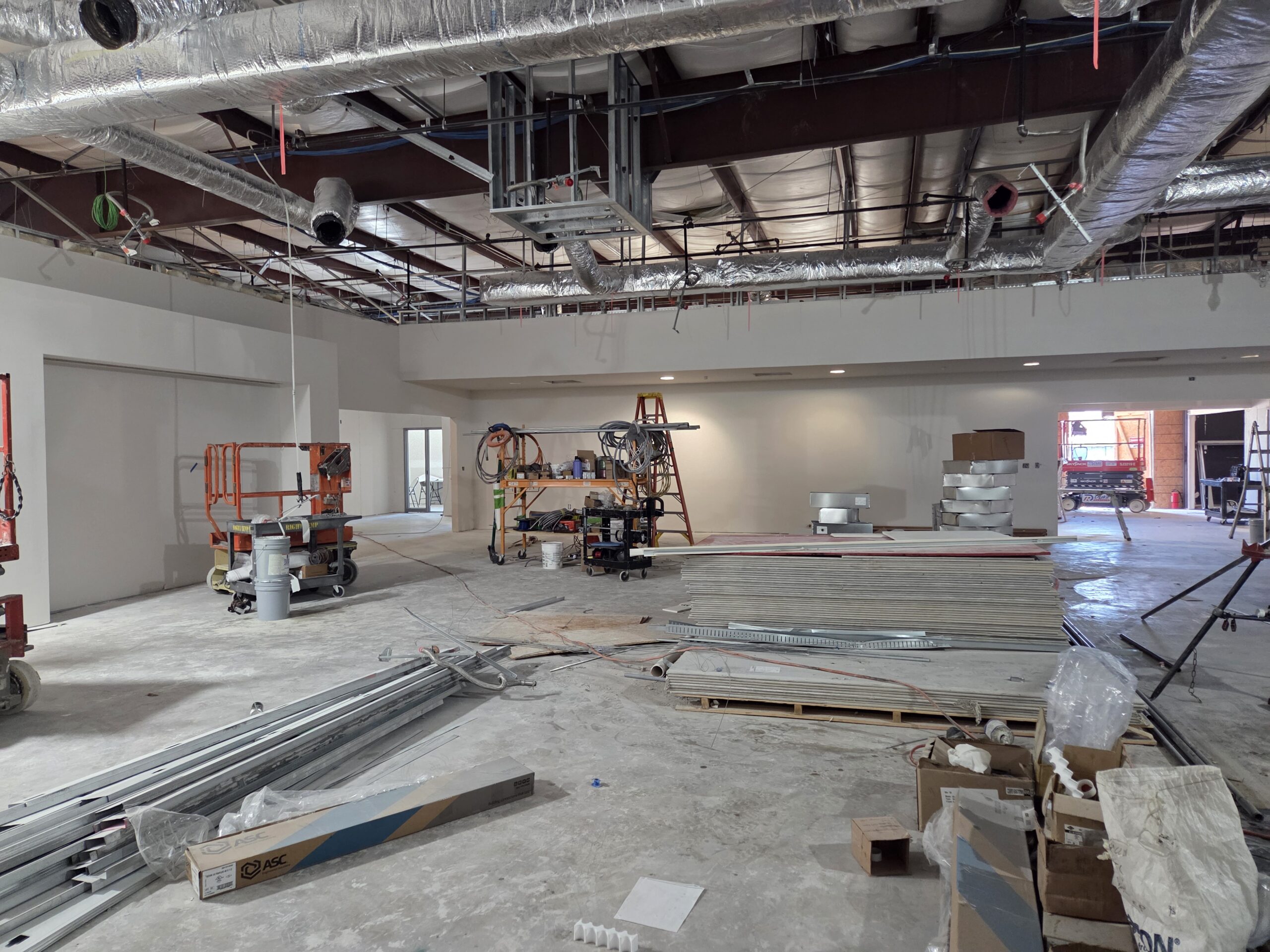 A big room with construction materials all over the floor. 